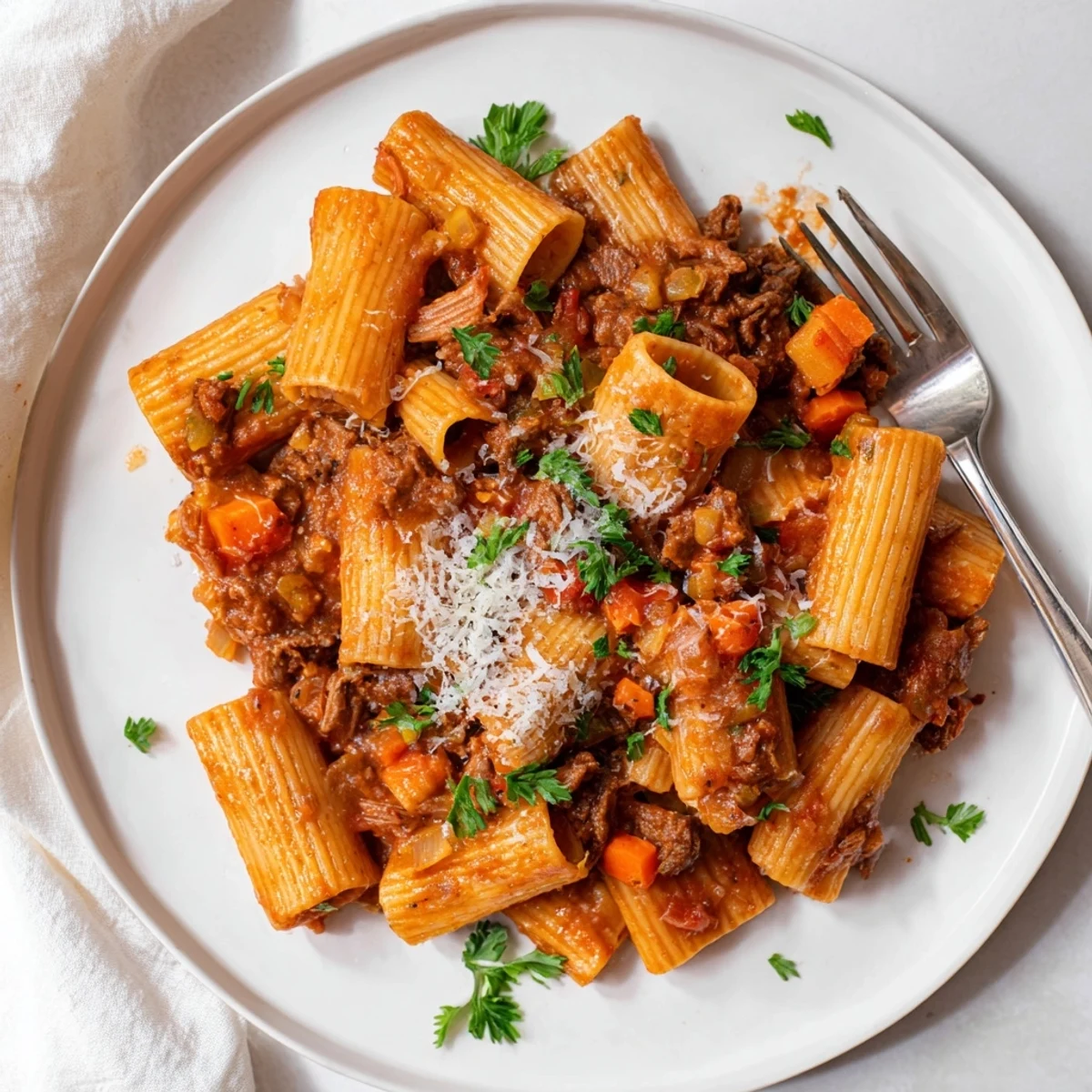 Tender beef chunks and aromatic vegetables simmer in a rich, slow cooker ragu, ready to be served over pasta.