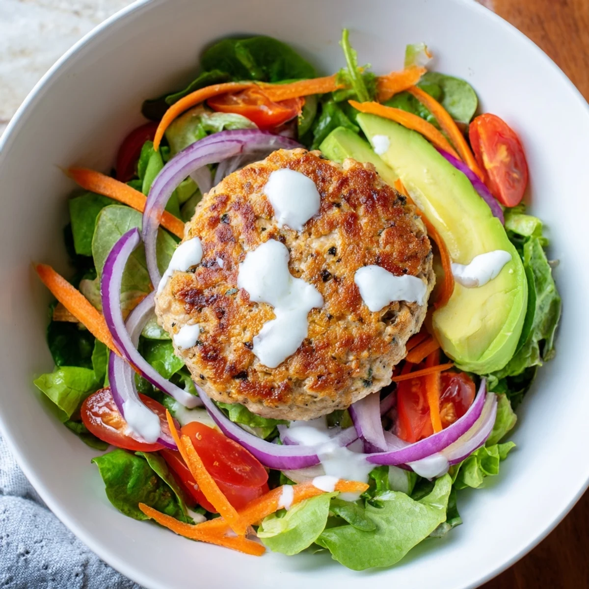 Healthy American dinner idea featuring a hearty Turkey Burger Salad Bowl with mixed greens, sliced red onion, and a drizzle of creamy yogurt dressing.