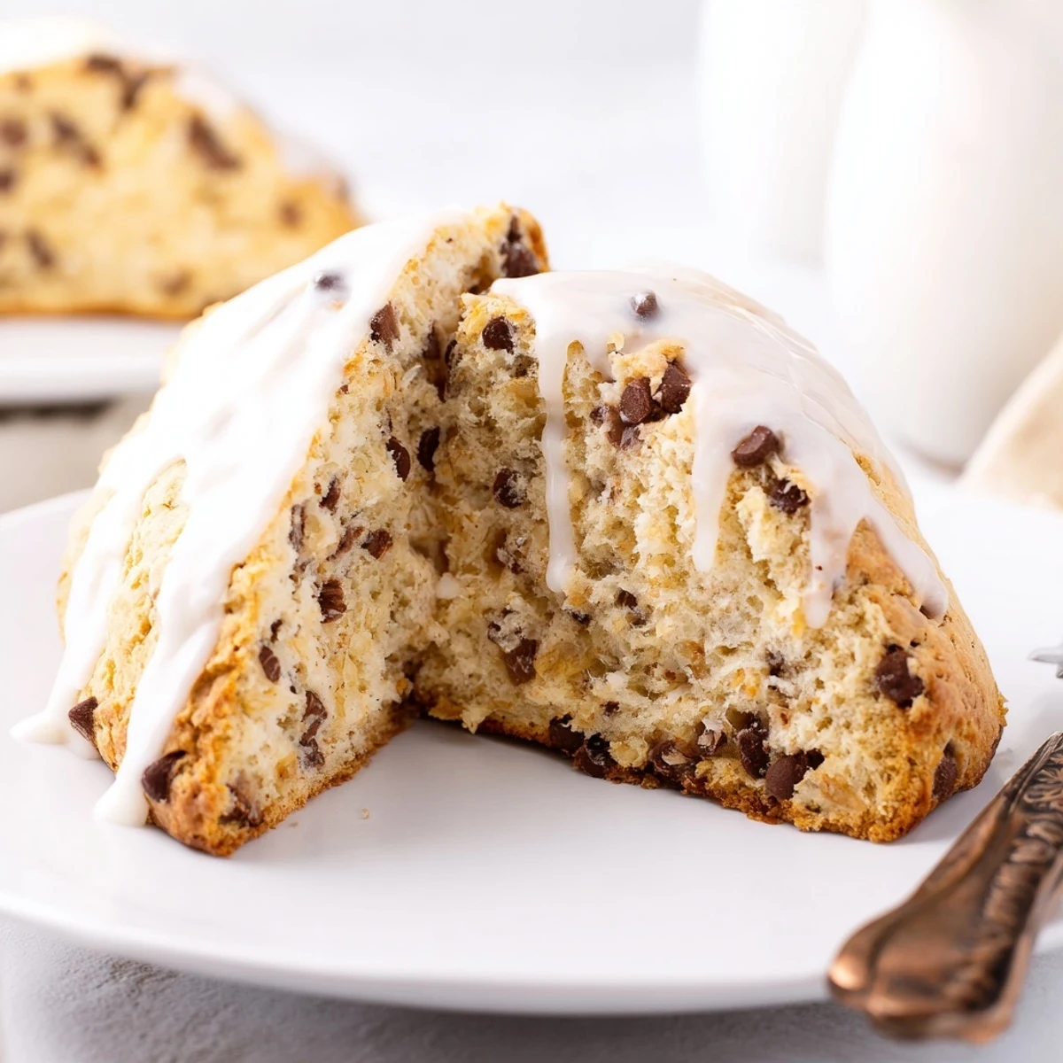 Two Chocolate Chip Scones with Glaze served on a plate with a cup of coffee, perfect for an American breakfast.