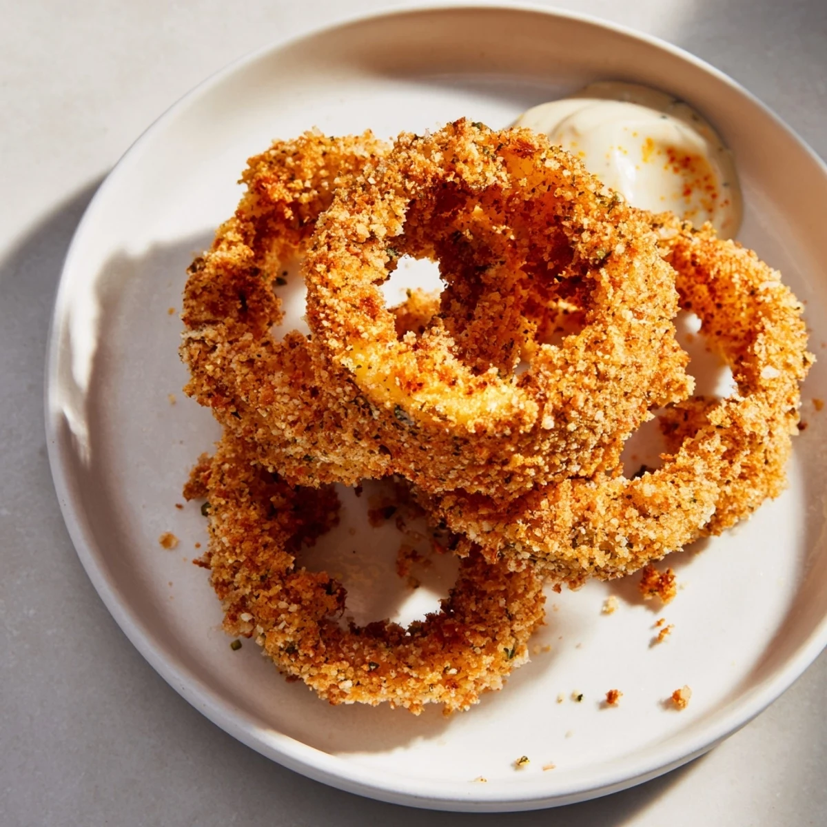 Close-up of Crispy Air Fryer Onion Rings with Spicy Mayo showing crunchy panko breading and a zesty drizzle.