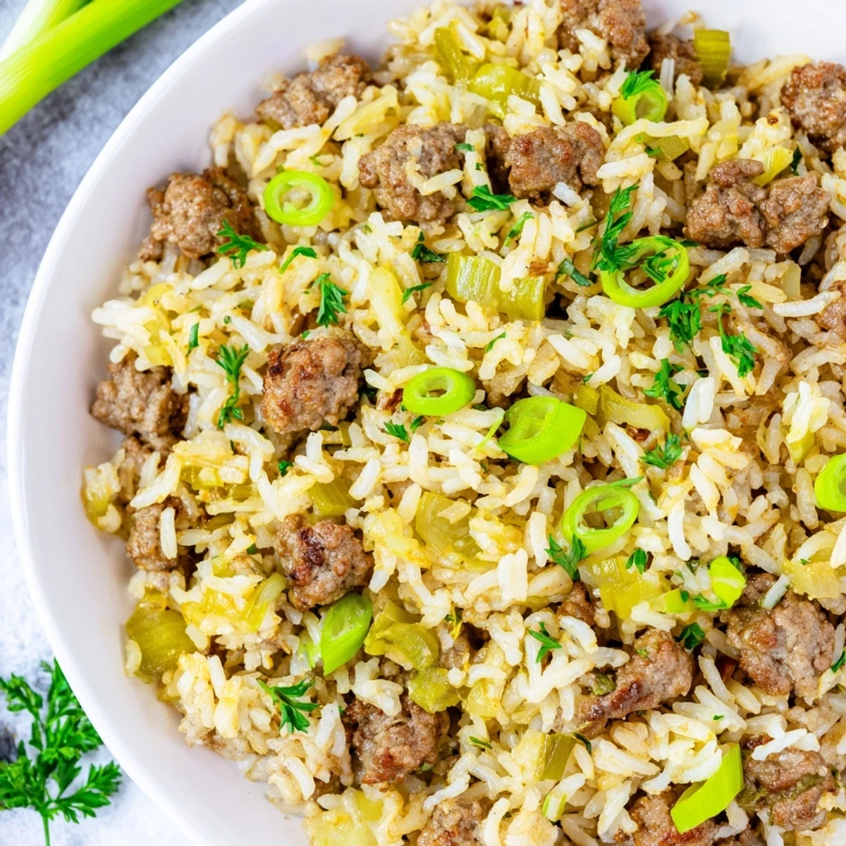 Cajun Dirty Rice with Ground Beef is served steaming in a rustic bowl, garnished with chopped parsley for a vibrant, flavorful presentation.  