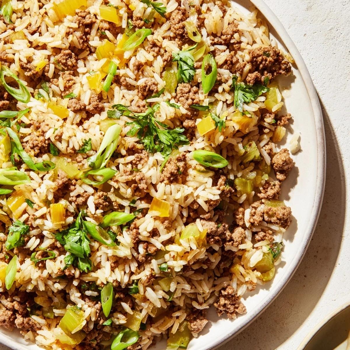 Hearty Cajun Dirty Rice with Ground Beef is plated alongside a side of hot sauce, ready for a satisfying weeknight dinner.