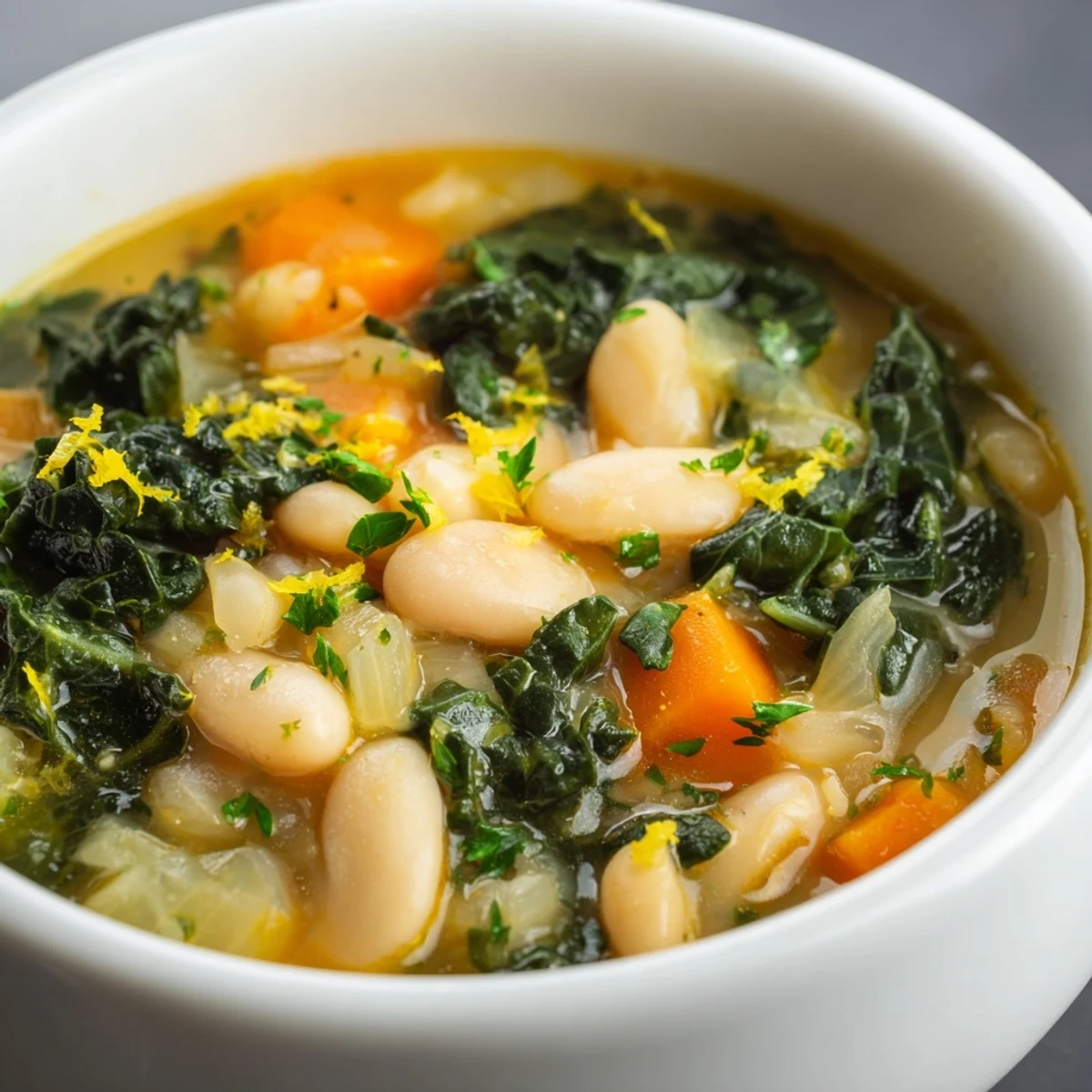 Bright lemon zest and steam rise from a hearty White Bean and Kale Soup, ready to serve.