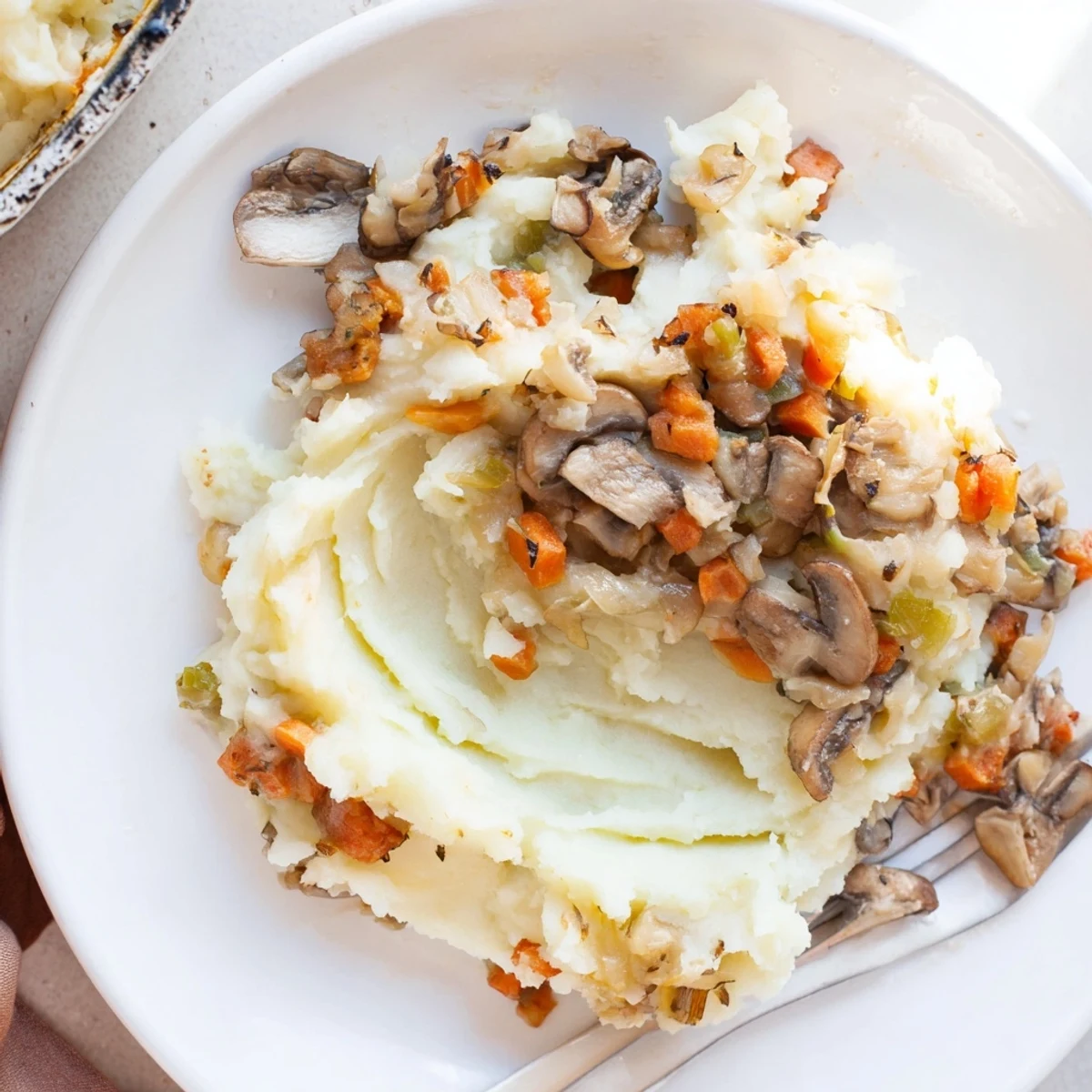 Close-up of a fork lifting a bite of mushroom and leek shepherds pie with thyme.