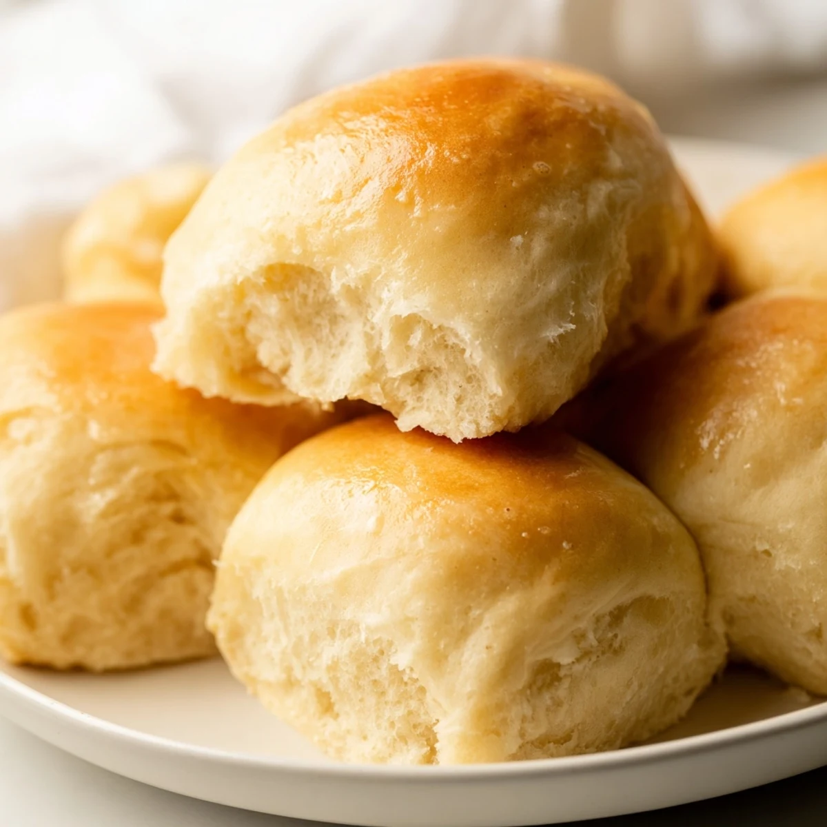 Close-up of soft Best Vegan Dinner Rolls on a linen napkin, ready to serve with a side of vegan butter.