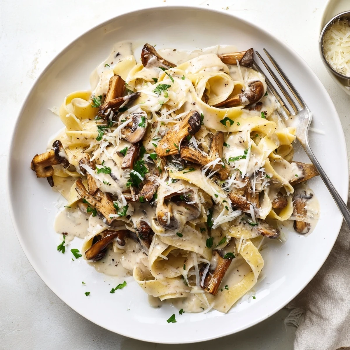 Steaming plate of Truffle Mushroom Pasta garnished with grated parmesan and chopped parsley, ready to enjoy with a glass of crisp white wine for date night.