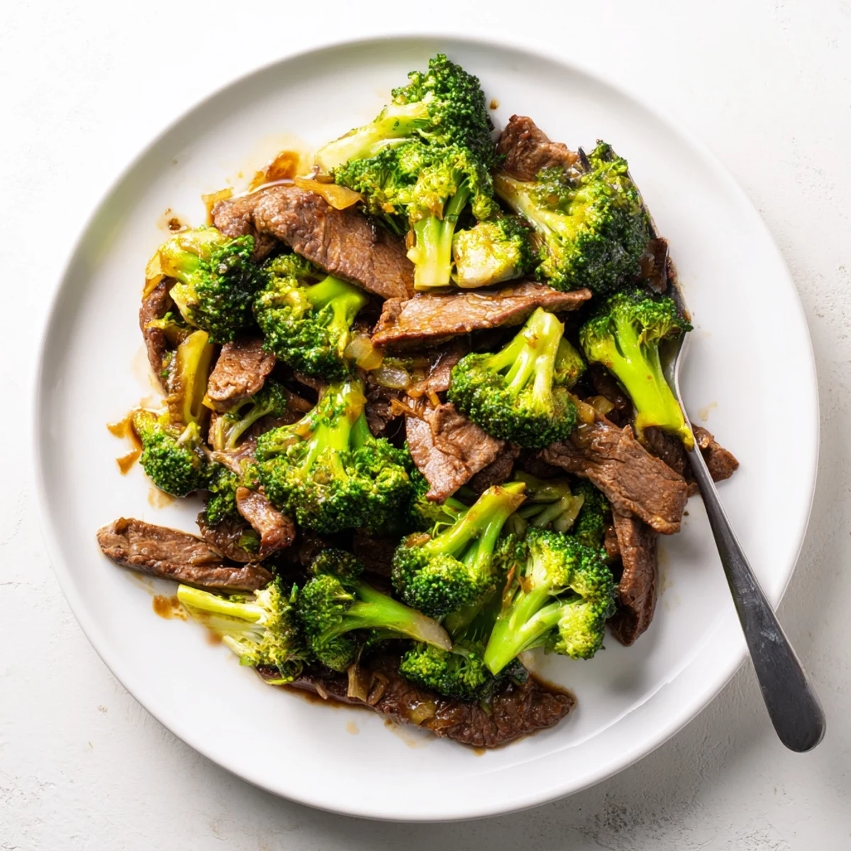 Chinese-American beef and broccoli dish served steaming with caramelized sauce coating vegetables