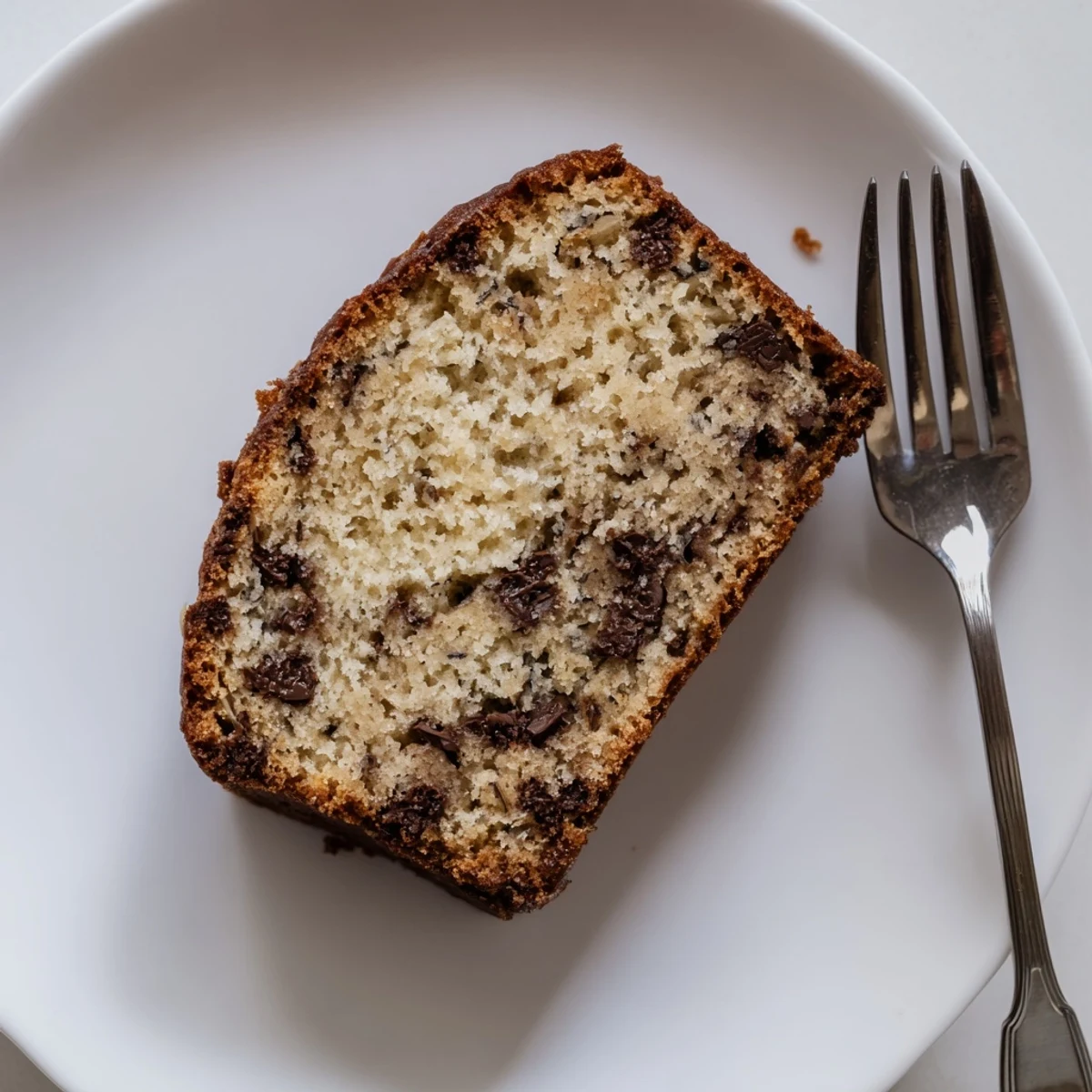 Golden brown chocolate chip banana bread loaf with melty chocolate chips on top