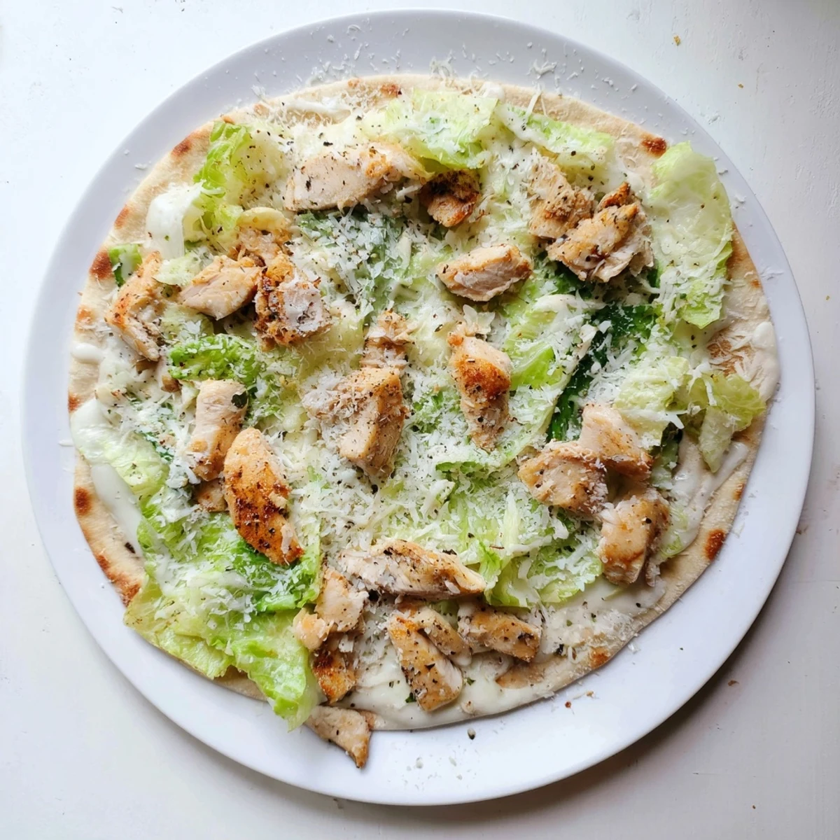Sliced chicken breast on crispy flatbread with Caesar dressing and fresh romaine