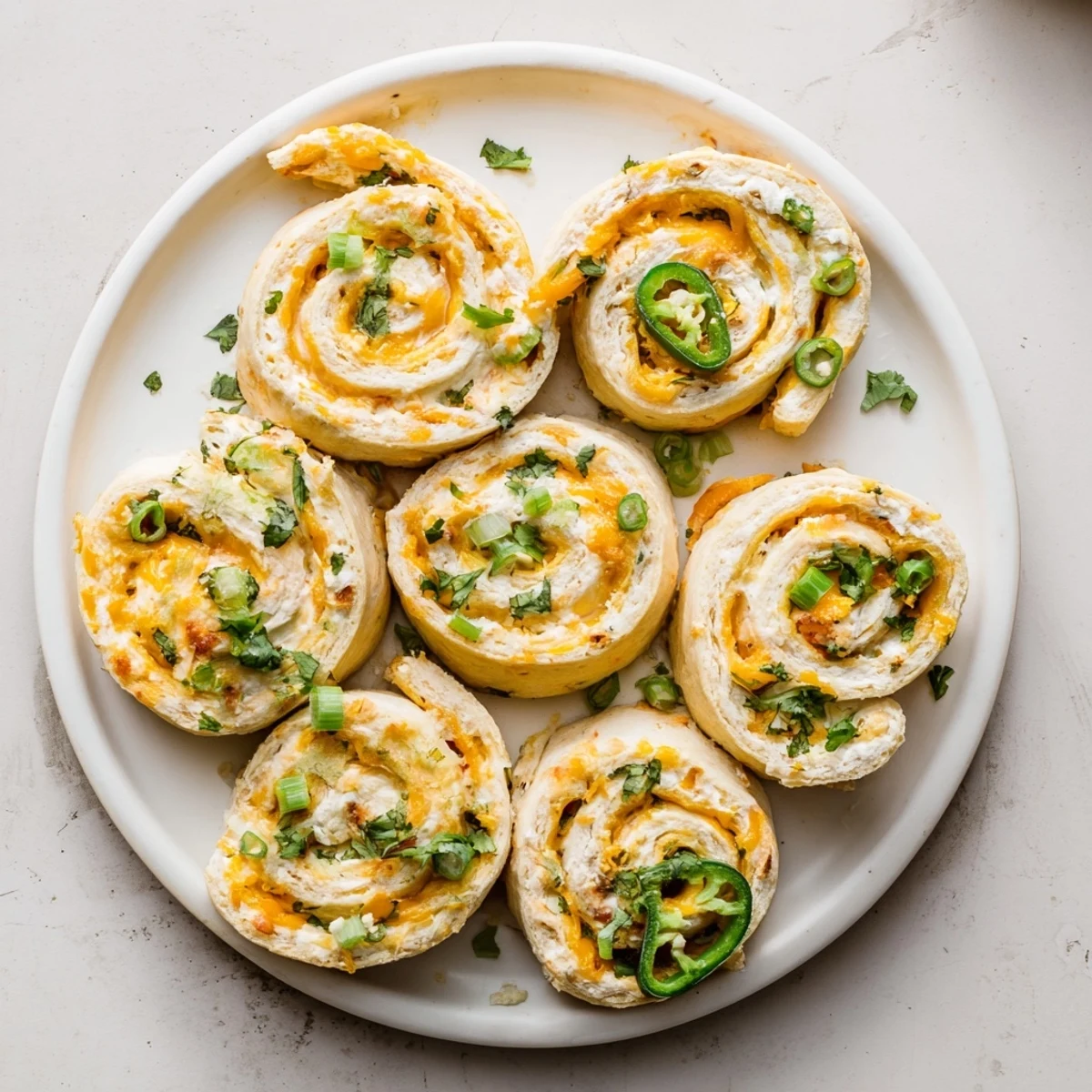 Spiral Easy Jalapeno Popper Pinwheels arranged on a wooden board showcasing creamy filling and vibrant diced peppers