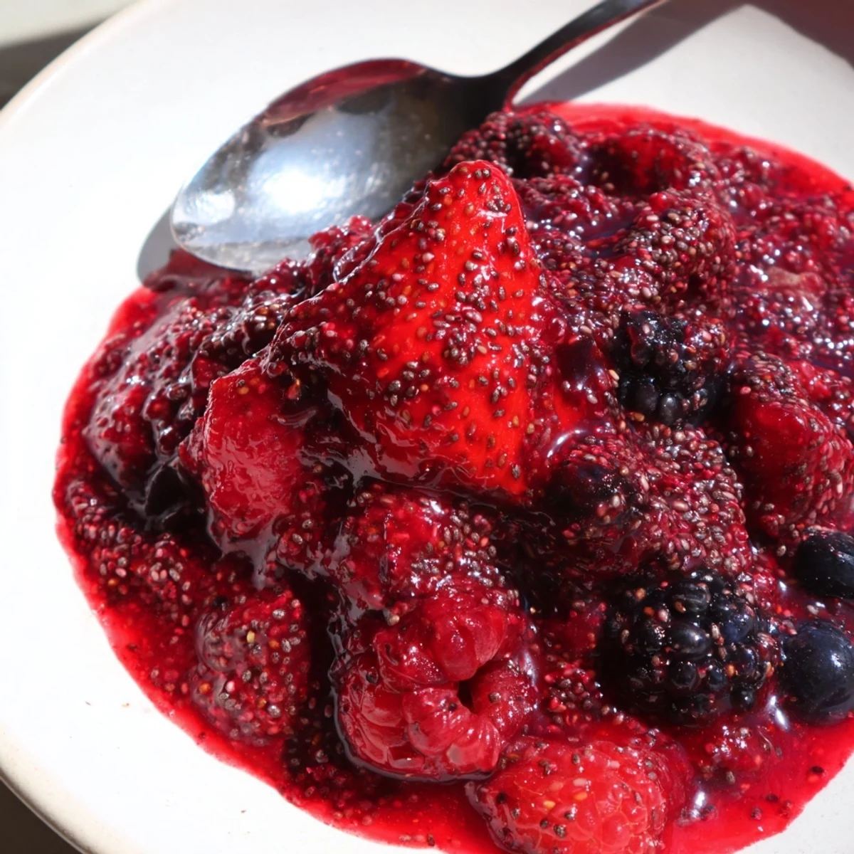 Spoonful of thick easy berry chia seed jam dripping generously over golden brown toasted sourdough bread