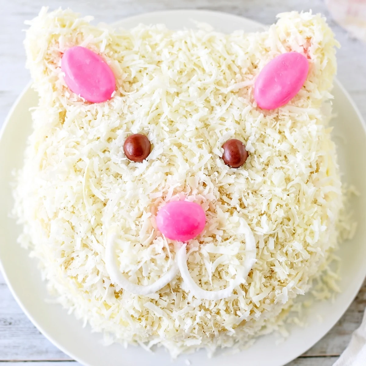 Adorable bunny cake decorated with fluffy white coconut and pink fondant ears for Easter celebrations