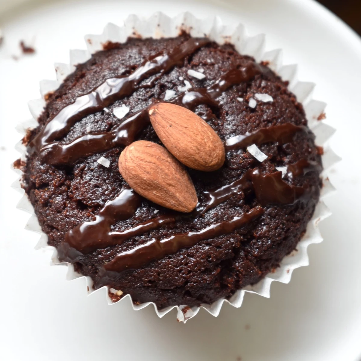 Rich flourless almond joy cupcakes topped with melted chocolate and roasted almonds