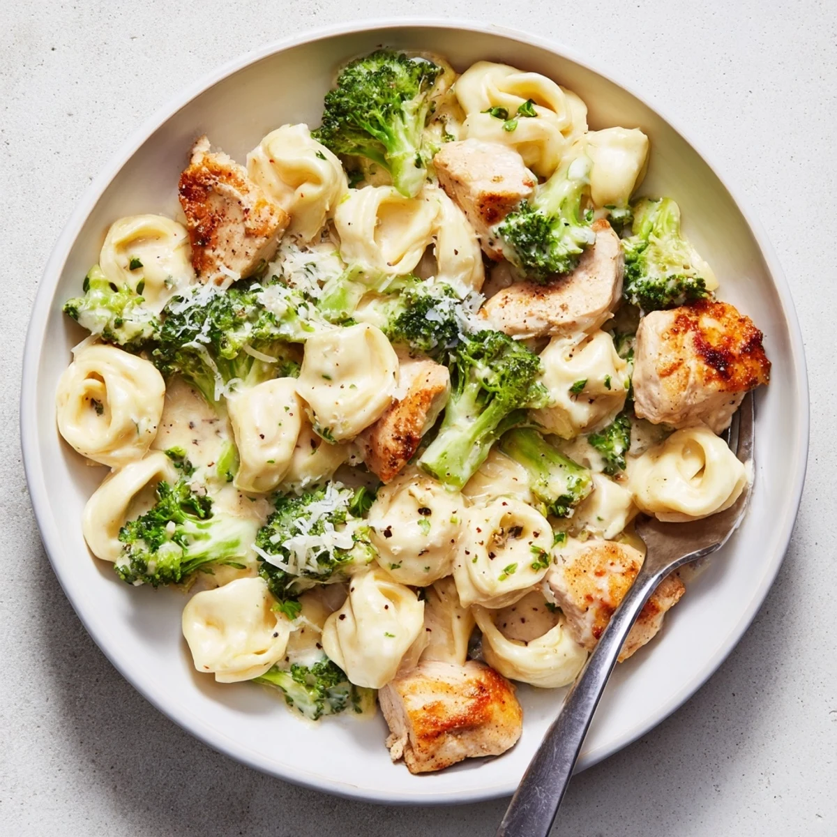 Creamy Garlic Parmesan Tortellini Chicken Broccoli Recipe steaming in skillet, Parmesan melting