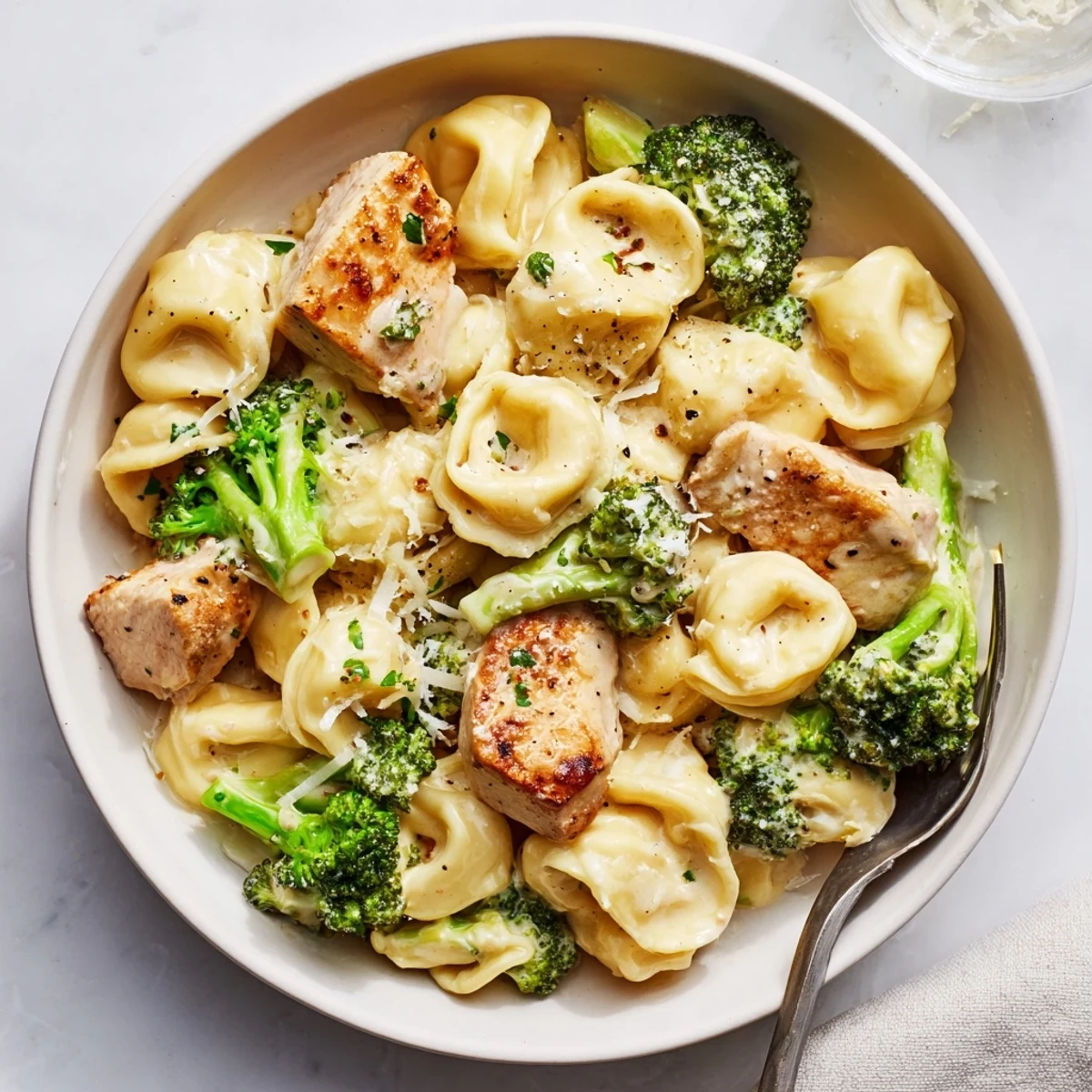 Fork-twirled Creamy Garlic Parmesan Tortellini Chicken Broccoli Recipe with juicy chicken bites