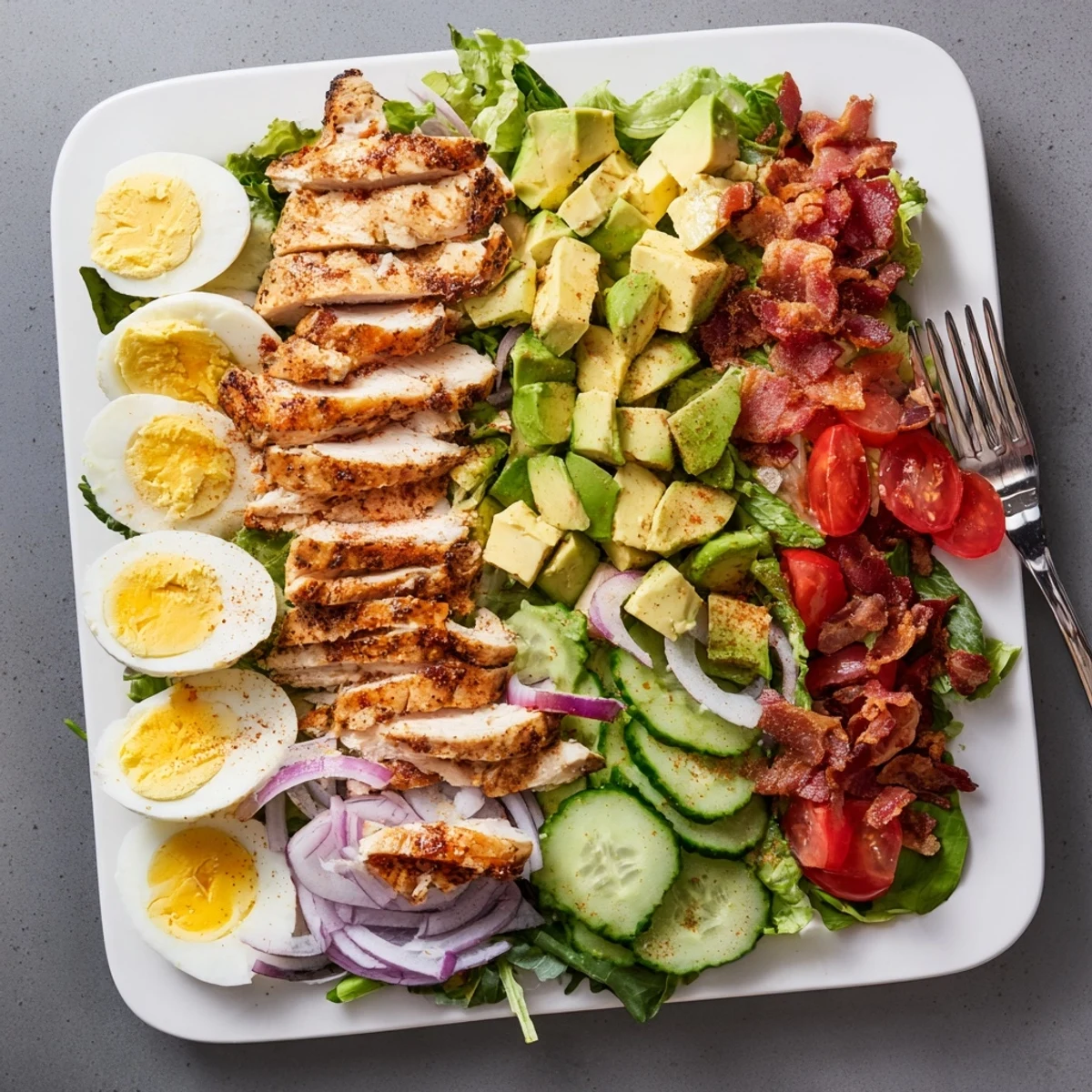 Golden grilled chicken strips atop a colorful Paleo Cobb salad with fresh avocado, bacon, and vegetables