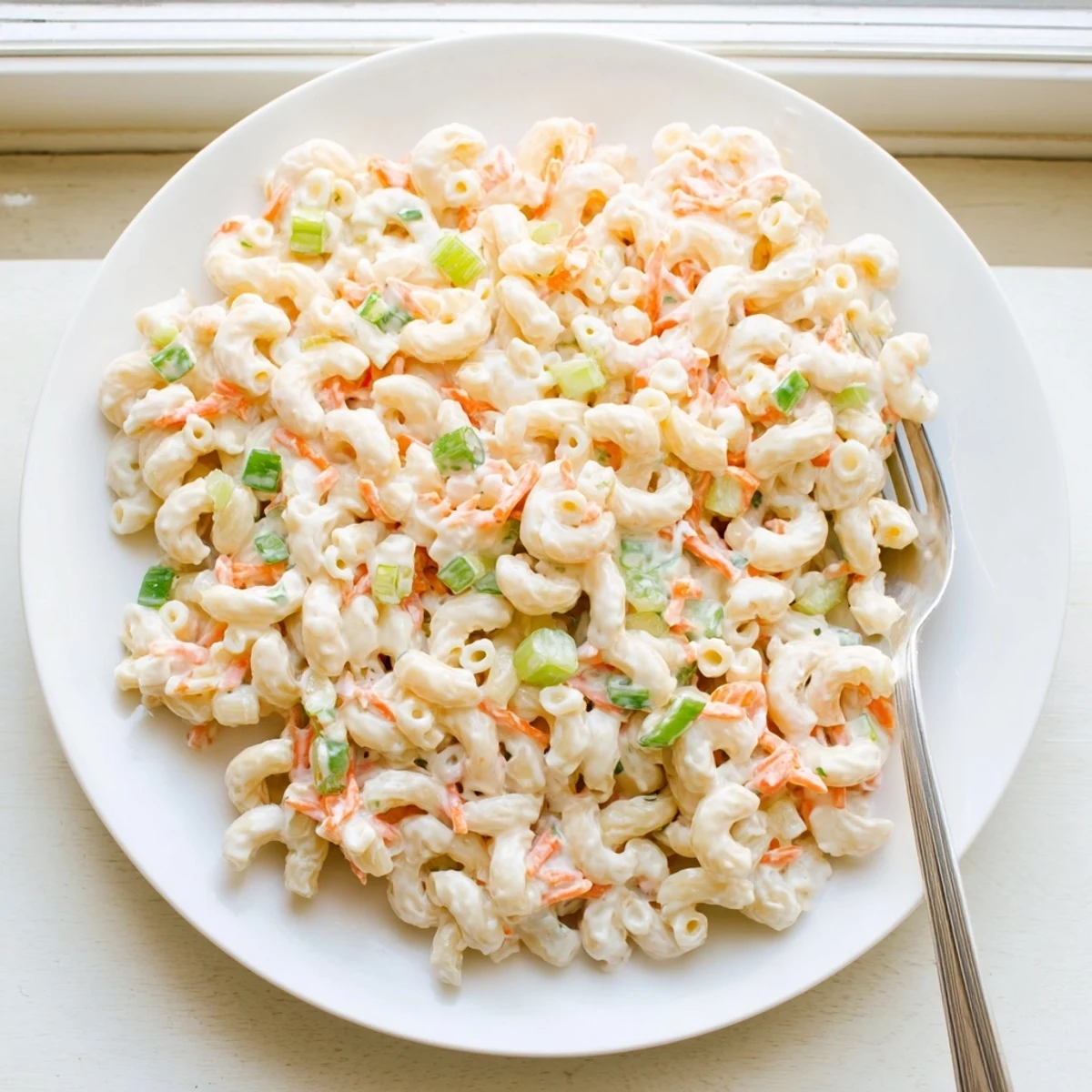 Close-up of Hawaiian style mac salad showcasing extra creamy dressing and finely chopped carrot and celery