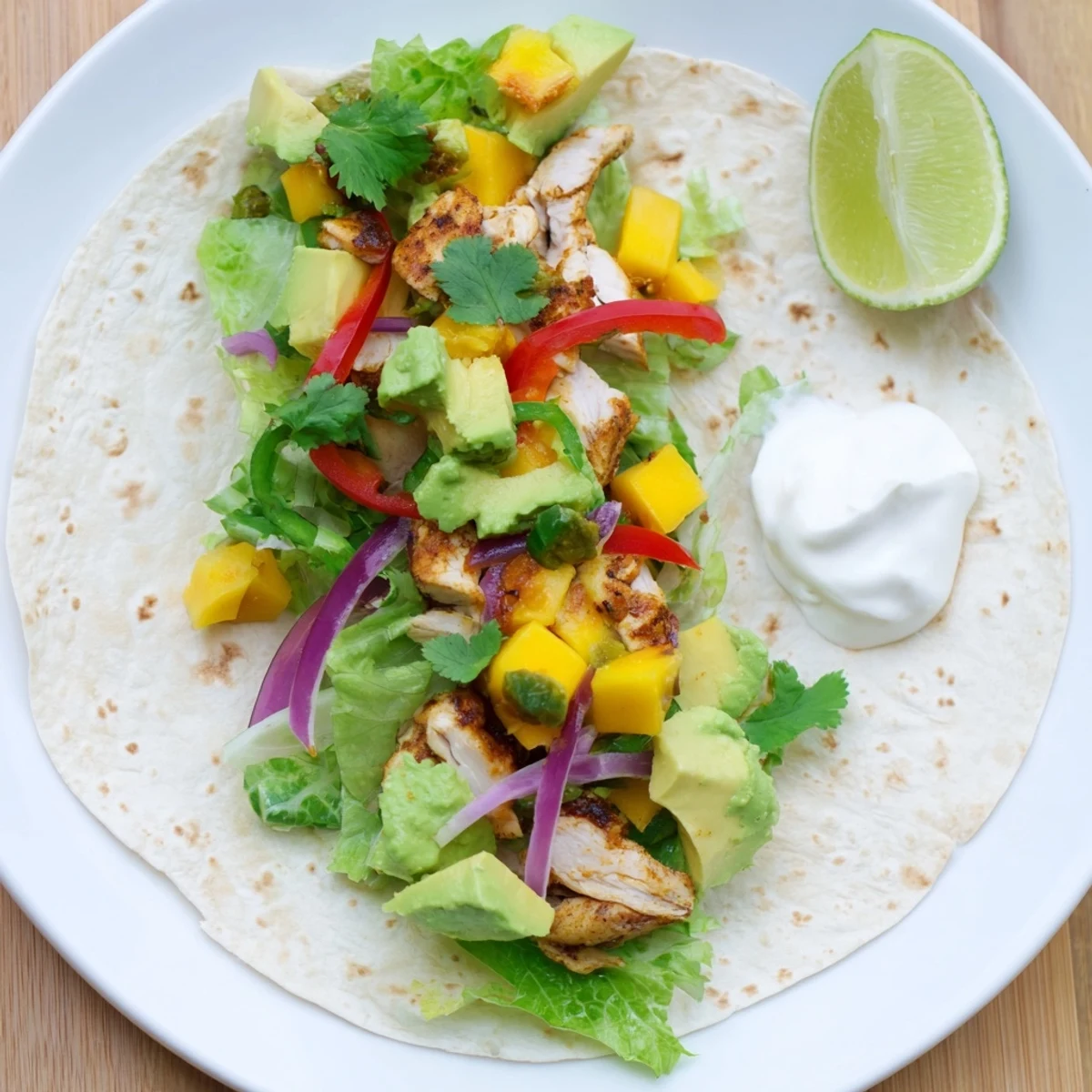 Fresh summer grilled chicken wraps stuffed with creamy avocado mango salsa and crisp green lettuce leaves