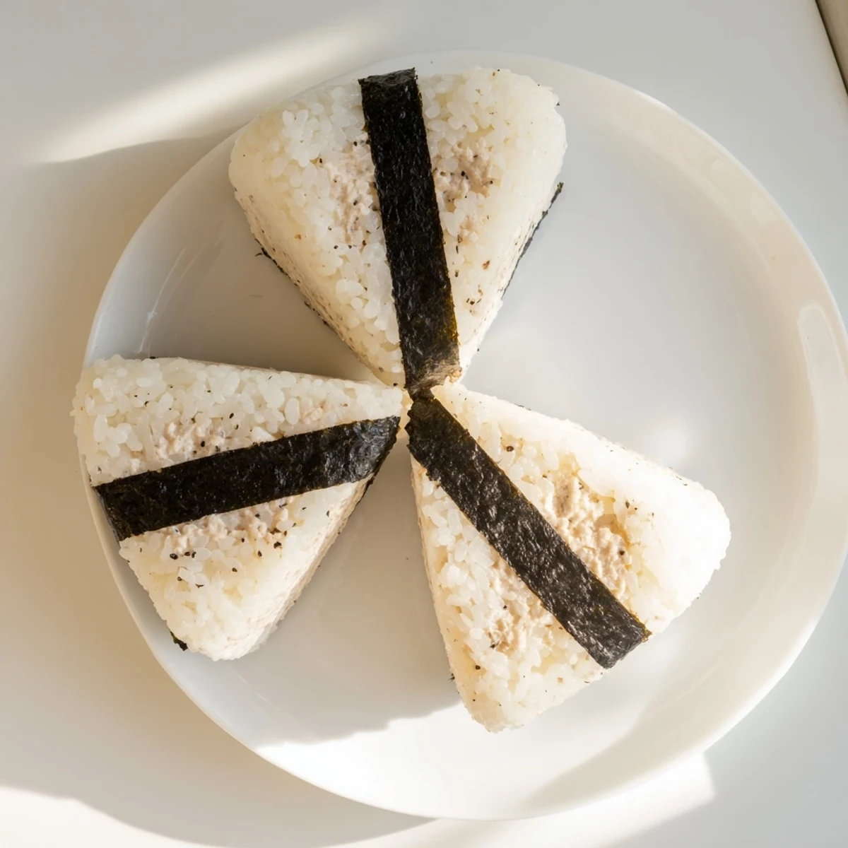White rice onigiri stuffed with flaky tuna mayo and garnished with black nori
