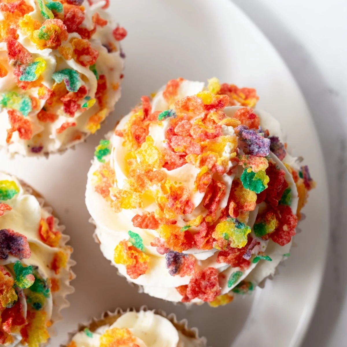 Creamy homemade Fruity Pebbles frosting featuring bright rainbow cereal pieces folded throughout