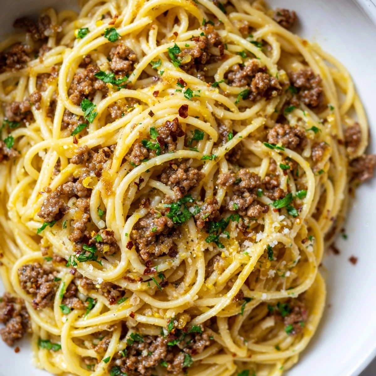 Steaming plate of garlic butter pasta with ground beef coated in rich silky sauce