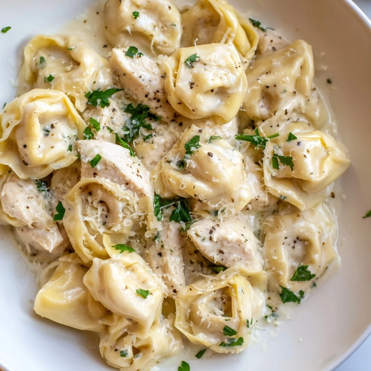 Plump homemade chicken tortellini swimming in rich buttery cream sauce topped with parsley