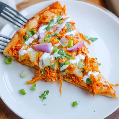 Freshly baked Bold Buffalo Chicken Pizza with creamy ranch dressing drizzles and bubbly golden cheese.
