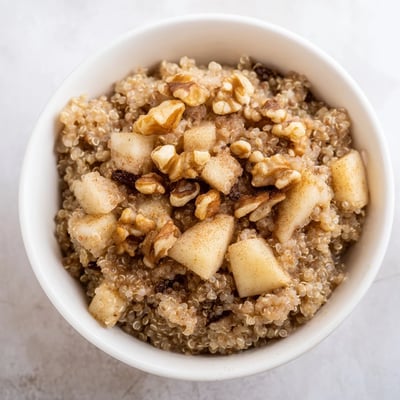 Healthy Quinoa Apple Breakfast served in a rustic ceramic bowl, featuring diced apples, creamy quinoa, and a sprinkle of nutmeg and raisins.